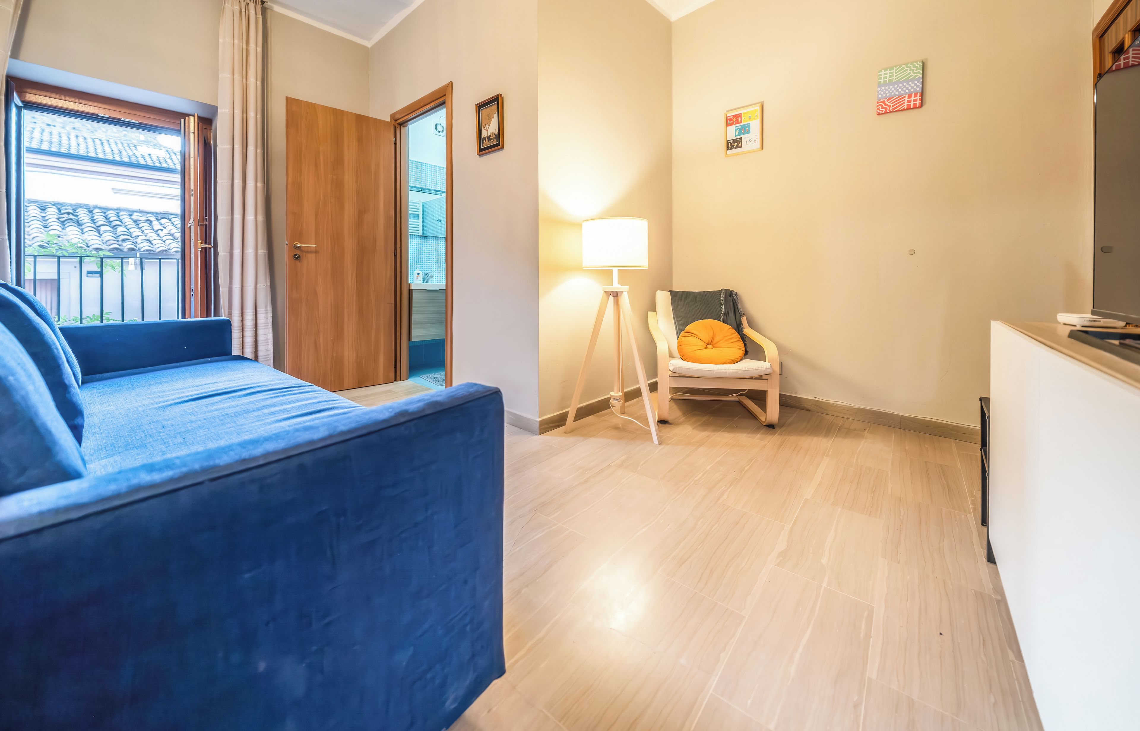 A room with a bed, a chair, a lamp, and a small table.