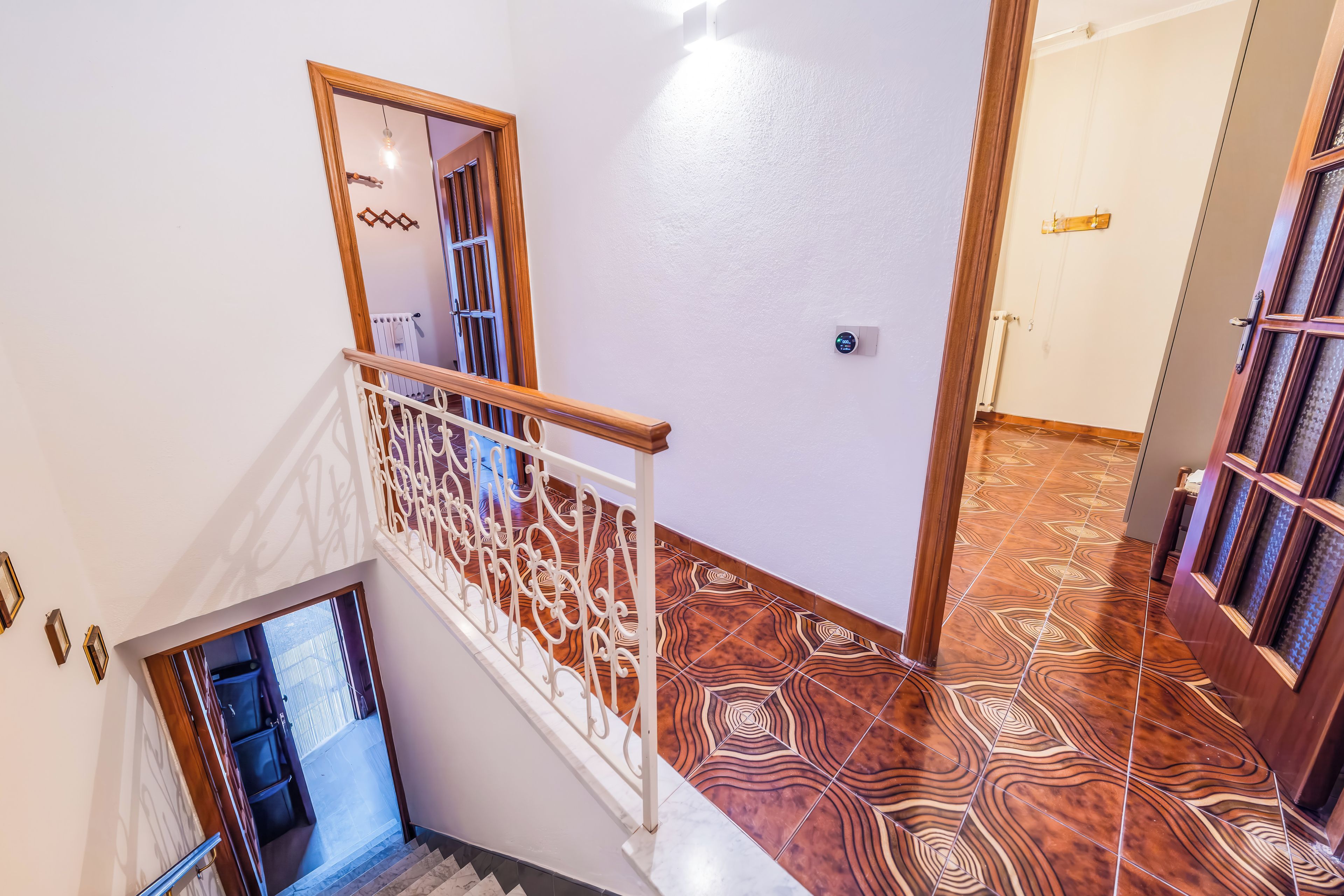 A staircase with a white railing and patterned floor tiles.