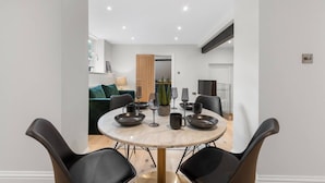 A modern dining area with a round table, black chairs, and a minimalist decor. - Modern & Historic Mill Flat With Garden View (Surrey)