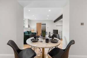 Een moderne eetruimte met een ronde tafel, zwarte stoelen en een minimalistische inrichting.