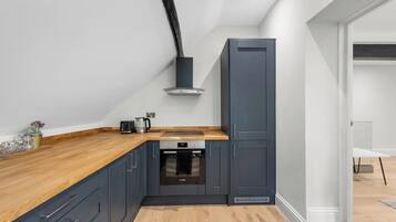A modern kitchen with dark cabinetry, a wooden countertop, and a built-in oven.