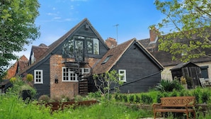 A traditional house with a prominent gable roof, a brick chimney, and a wooden bench in the garden. - Modern & Historic Mill Flat With Garden View (Surrey)