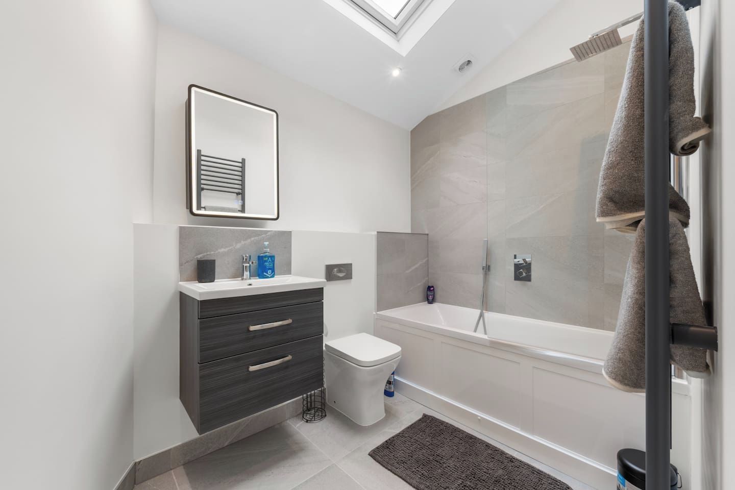 Une salle de bain moderne équipée d’une douche, de toilettes et d’un meuble-lavabo.