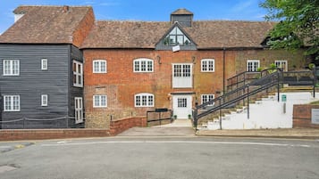 A two-story building with a brick facade, a staircase leading to the entrance, and a gated driveway.