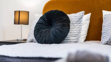 A bed with a headboard, pillows, and a bedside lamp.