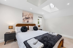 Een slaapkamer met een bed, nachtkastjes, een dakraam en een schilderij aan de muur.