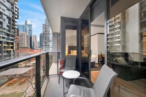 Ein Balkon mit Blick auf eine Stadtlandschaft, ein kleiner Tisch und ein Stuhl.