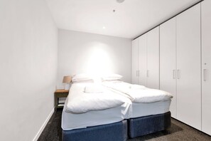 Une chambre à coucher avec un lit, une table de chevet, une lampe et une armoire.