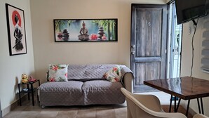 En stue med sofa, spisebord, fjernsyn og en dør.