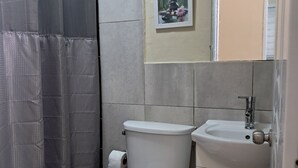 Et badeværelse med toilet, håndvask og bruseforhæng.