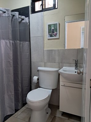 Un baño con inodoro, lavamanos y cortina de ducha.