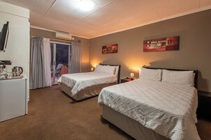 Habitación de hotel con dos camas, un escritorio con hervidor y vistas al exterior.
