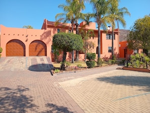 Um edifício com calçada, garagem e jardim bem cuidado com diversas plantas.