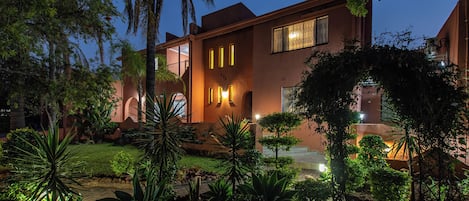 A modern building with a well-maintained garden, a visible entrance, and a clear sky.