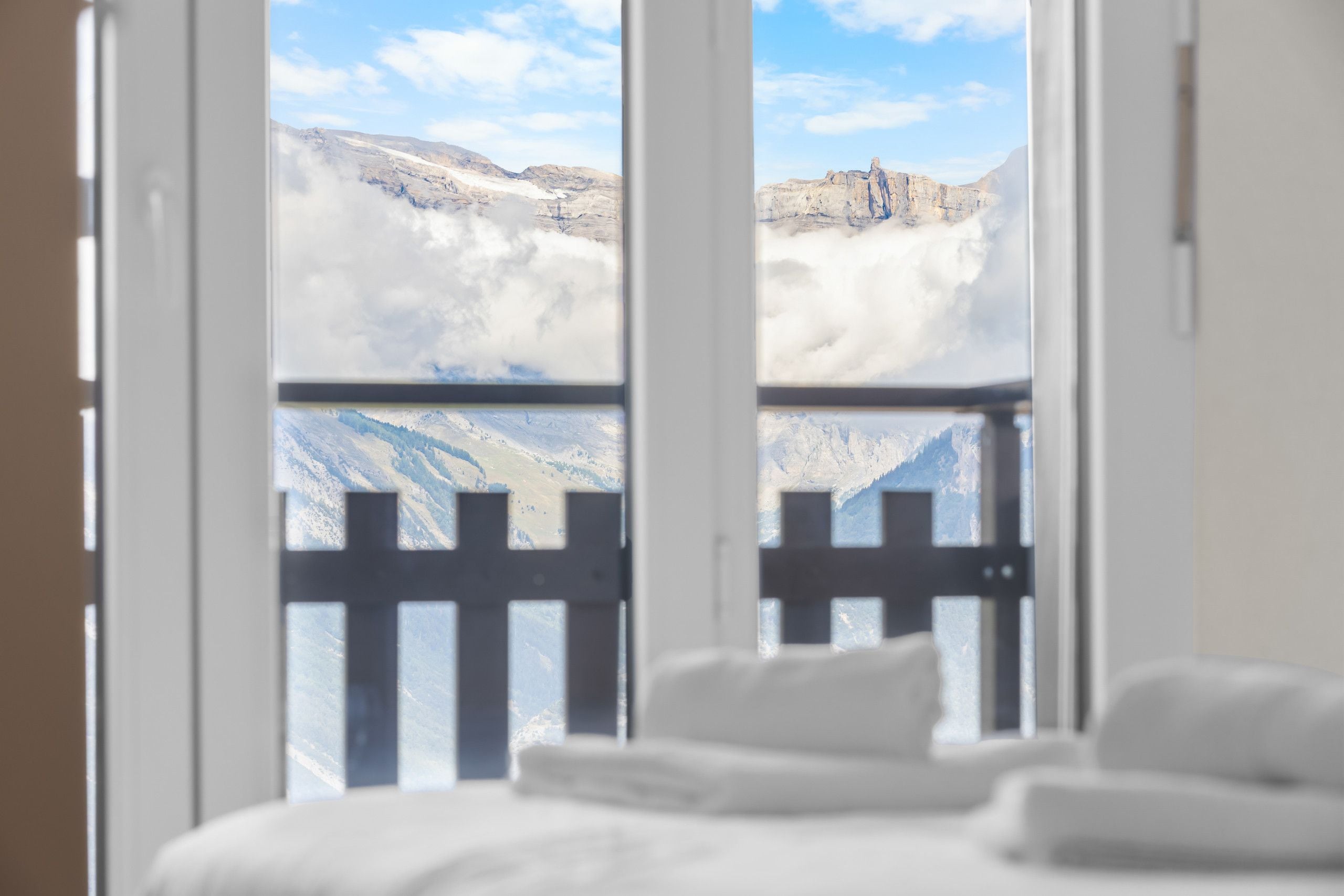 Une chambre d’hôtel avec un lit et une vue sur un paysage montagneux, visible à travers de grandes fenêtres.