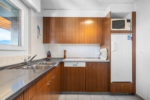 Eine moderne Küche mit Holzschränken, einer Edelstahl-Spüle und einem weißen Kühlschrank.