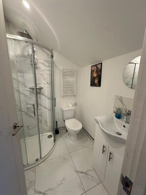 A bathroom with a glass-enclosed shower, a toilet, a sink, and a mirror. - Apartment Sleeps 3 Near High Street (Thornton Heath)