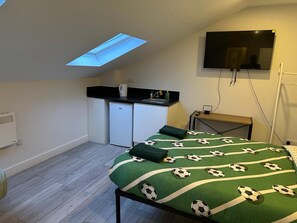 A compact room with a bed, a kitchenette, a TV, and a skylight. - Apartment Sleeps 3 Near High Street (Thornton Heath)