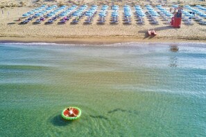 A beach with rows of umbrellas and a lifeguard tower.