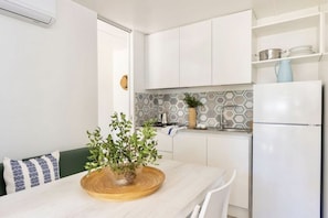 A modern kitchen with white cabinetry, a hexagonal backsplash, and a built-in refrigerator.