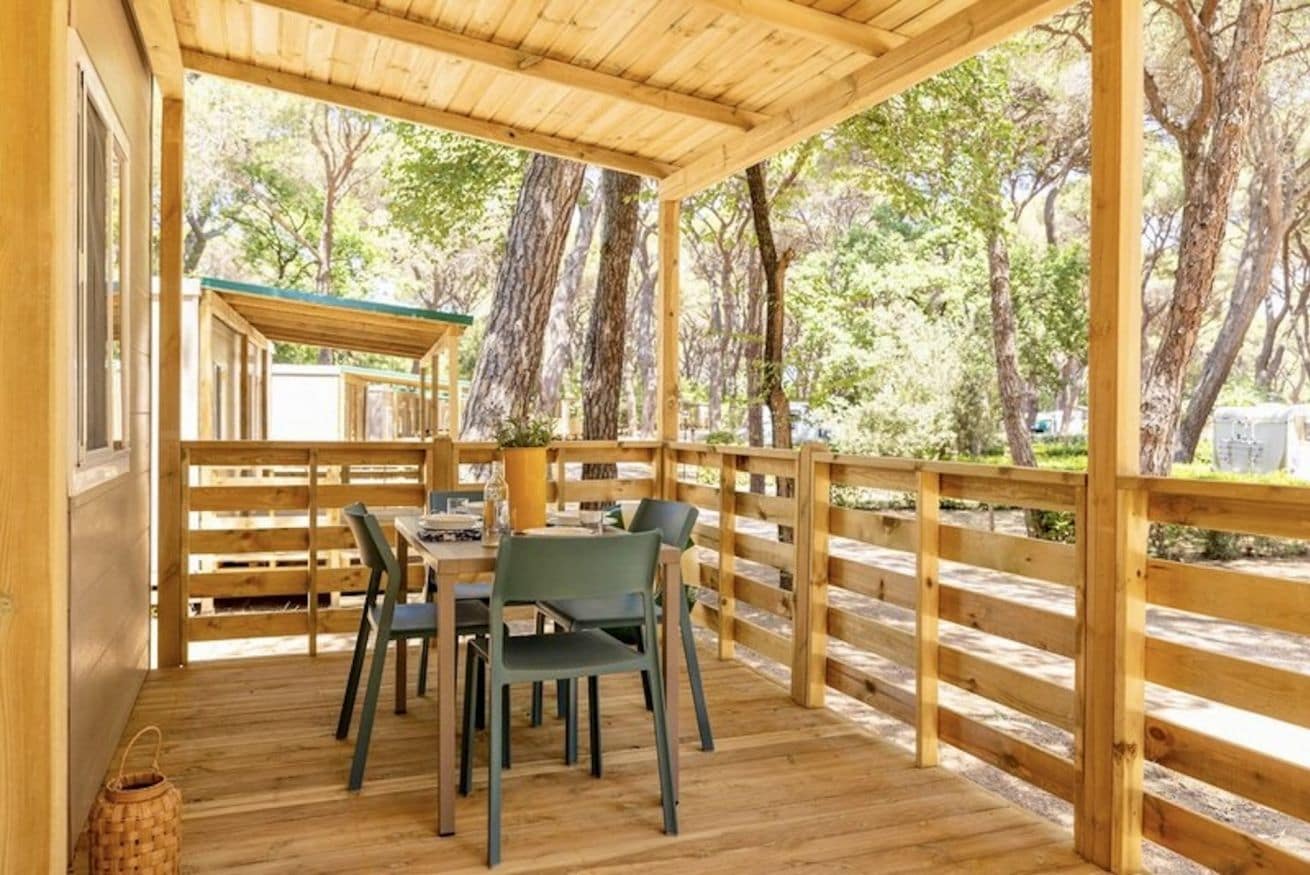A wooden deck with a table and chairs, surrounded by a wooden railing.