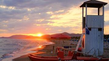 A lifeguard tower, a red lifeboat, and a beach umbrella.