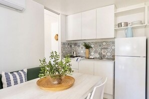 A modern kitchen with white cabinetry, a hexagonal backsplash, and a built-in refrigerator.