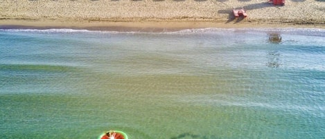 A beach with rows of umbrellas and a lifeguard tower.