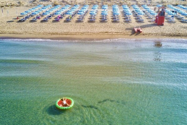 A beach with rows of umbrellas and a lifeguard tower.