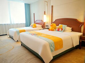 A hotel room with two beds, each with a plush toy and a pillow.