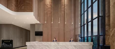 A modern reception area with a marble counter, large windows, and a unique hanging light fixture.