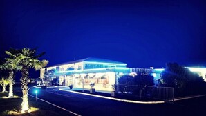 A hotel with a prominent restaurant sign, a well-lit entrance, and a parking area. - Hotel Le Capricorne Rest. Le Trianon (Marmande)