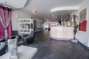 Eine moderne Hotelhalle mit einer Rezeption, einer Sitzecke und einer großen Vase auf einem Tisch.