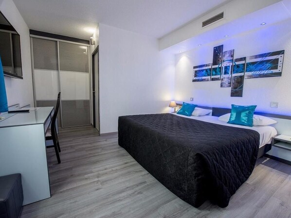 A modern hotel room with a bed, a desk, and a chair. - Hotel Le Capricorne Rest. Le Trianon (Marmande)