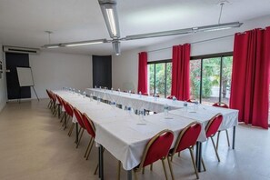 A conference room with a long table, red chairs, and a whiteboard. - Hotel Le Capricorne Rest. Le Trianon (Marmande)