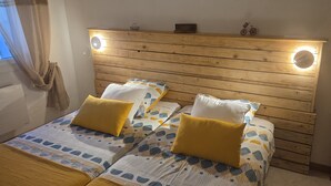Una cama doble con cabecera de madera, dos almohadas y una colcha estampada.