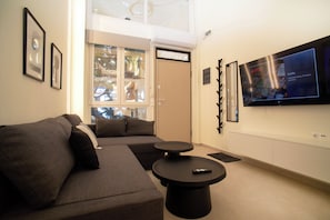 Ein modernes Wohnzimmer mit einem Ecksofa, einem runden Couchtisch und einem flachbildfernseher an der Wand.