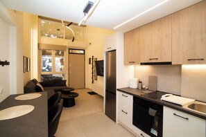 Eine moderne Küche mit eingebautem Backofen, einem Kühlschrank und einer Essecke mit Tisch und Stühlen.