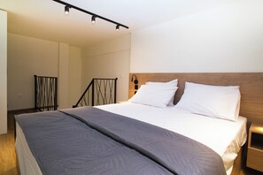 A hotel room with a large bed, a wooden headboard, a nightstand, and a staircase with a metal railing. - Welcome Loft I, near Papafi Metro & City Center (Thessaloniki)