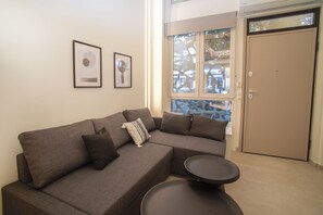 Ein modernes Wohnzimmer mit einer Eckcouch, einem kleinen runden Tisch und zwei gerahmten Kunstwerken an der Wand.