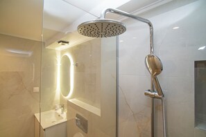 Un baño moderno con ducha envuelta en vidrio, tocador con espejo y retrete.