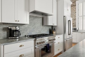 A modern kitchen with white cabinetry, a stainless steel range, and a built-in oven. - The Conroy | Perfect Location | Historic Charm (Charleston)