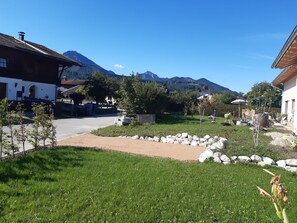 Ein Wohngebiet mit befestigter Auffahrt, einem Rasen und einem Kiesweg, der zu einem Haus mit Blick auf das Gebirge führt.