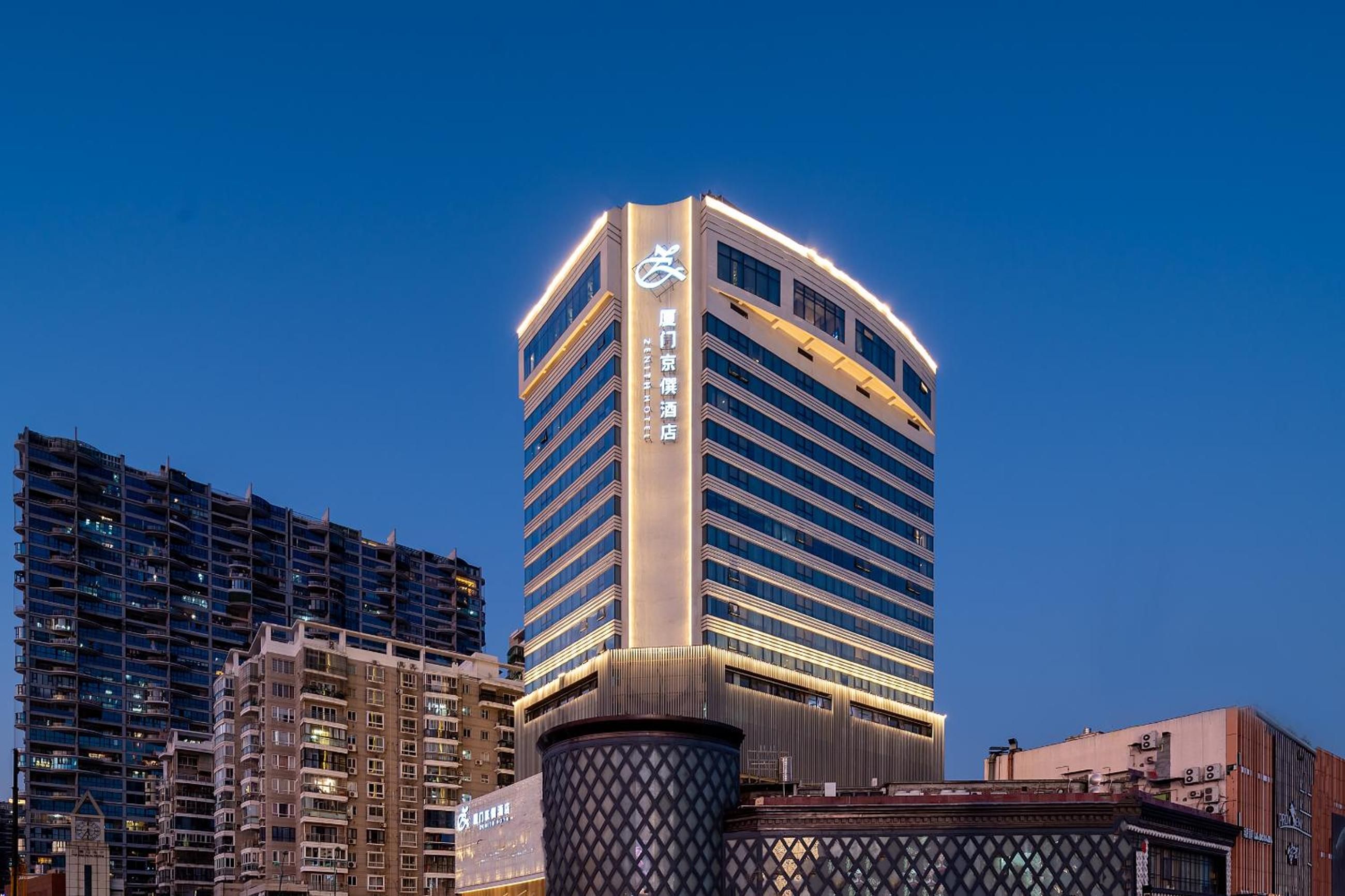 A high-rise hotel with a modern design, featuring a prominent logo on the facade.