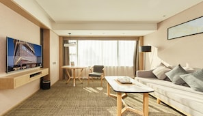 A hotel room with a flat-screen TV, a sofa, a dining table, and a large window with curtains. - Xiamen United Hotel (Xiamen)