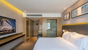 A hotel room with a large bed, a TV mounted on the wall, and a view of the outside. - Xiamen United Hotel (Xiamen)