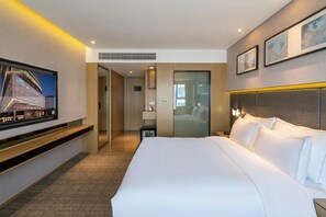 A hotel room with a large bed, a TV mounted on the wall, and a view of the outside. - Xiamen United Hotel (Xiamen)