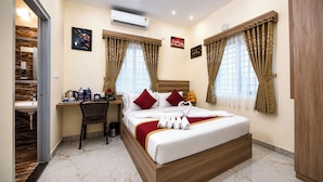 A hotel room with a bed, a desk, a chair, a sink, and a shower area. - HOTEL STAY BLISS - HSR LAYOUT (Bengaluru)