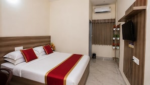A hotel room with a bed, a television, an air conditioning unit, and a small plant on a shelf. - HOTEL STAY BLISS - HSR LAYOUT (Bengaluru)