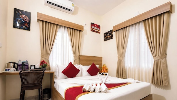 A hotel room with a bed, a desk, a chair, and a window with curtains. - HOTEL STAY BLISS - HSR LAYOUT (Bengaluru)